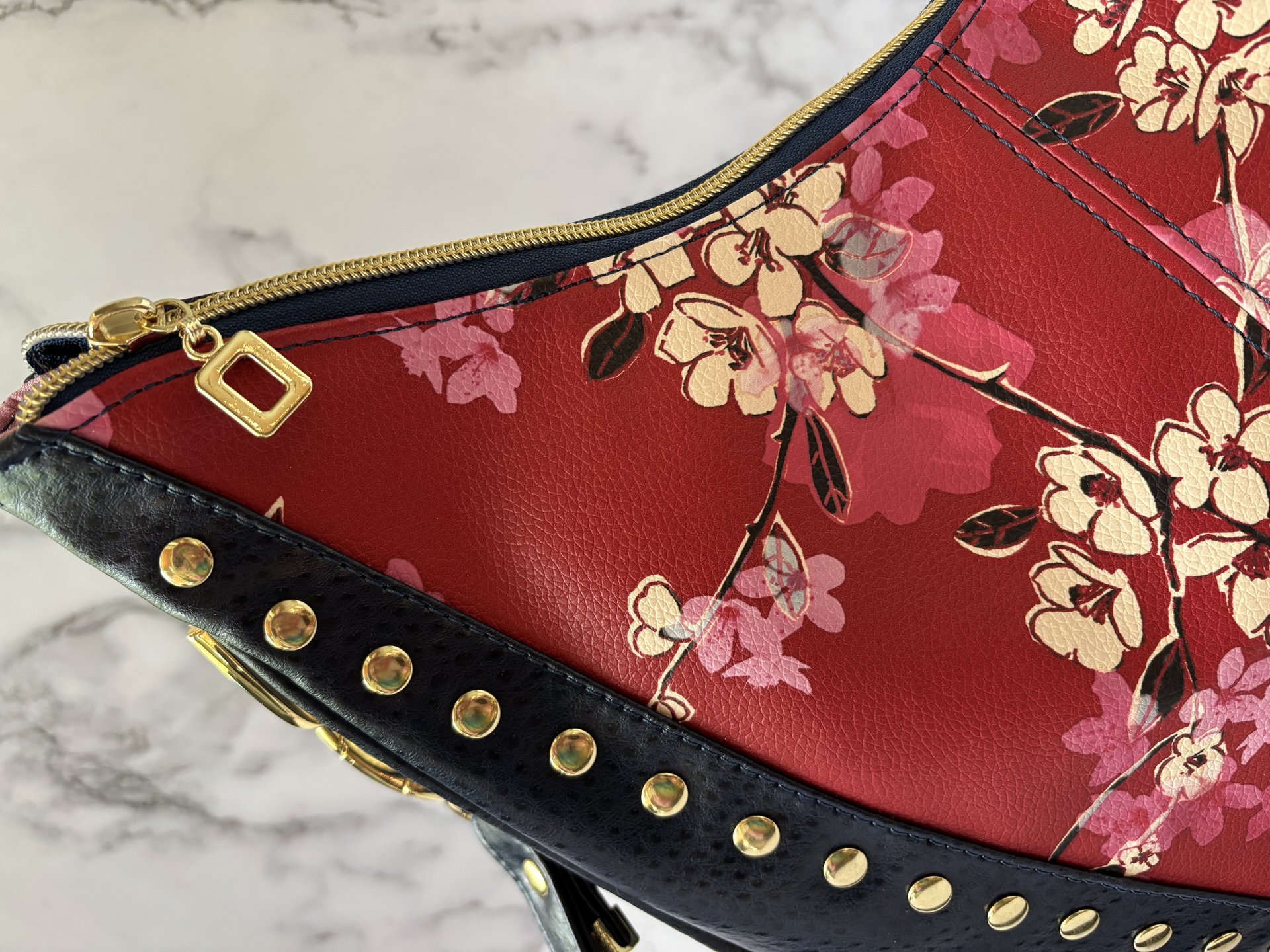 Curved semi-slouchy handbag with matching eyewear/sunglass case, in a floral pattern in cream, pink, and maroon tones, with a rich solid navy